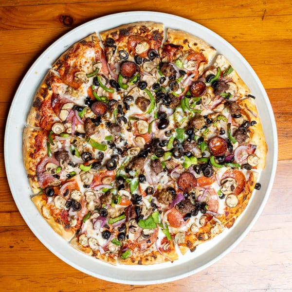 A large, sliced pizza with pepperoni, sausage, mushrooms, olives, green peppers, and onions.