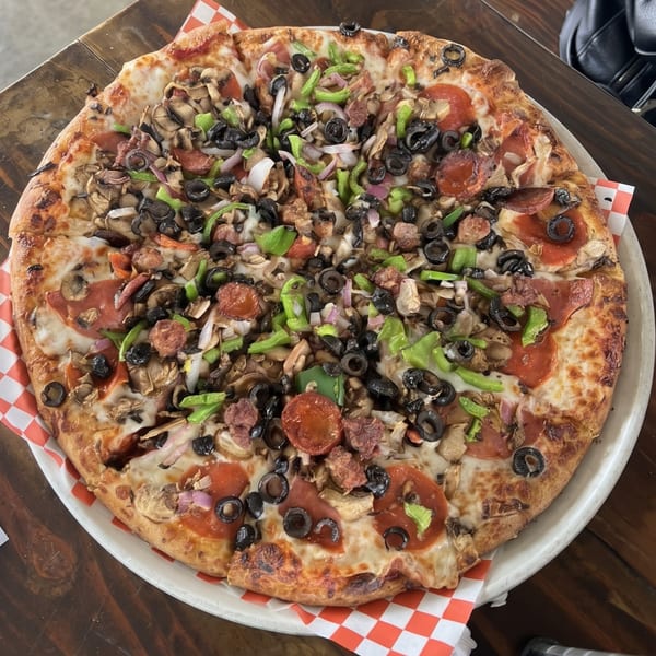 A whole pizza with pepperoni, sausage, mushrooms, olives, green peppers, and onions.