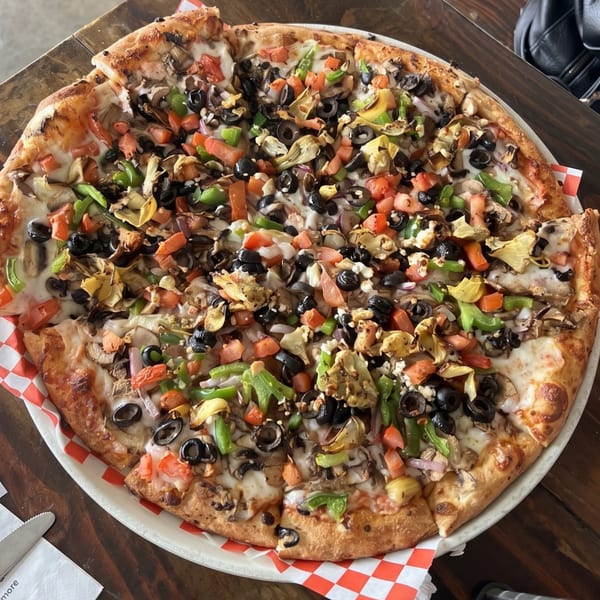 Large vegetarian pizza with olives, bell peppers, tomatoes, mushrooms, and artichoke hearts.